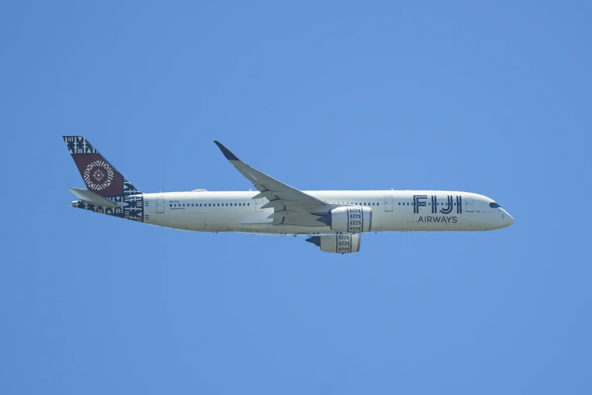 Fiji Airways Airbus A350 flies against a clear blue sky, showcasing its unique livery.