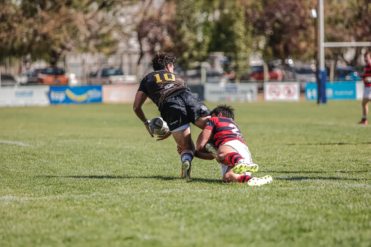 Dynamic rugby tackle during an outdoor match with players in action on a sunny day.